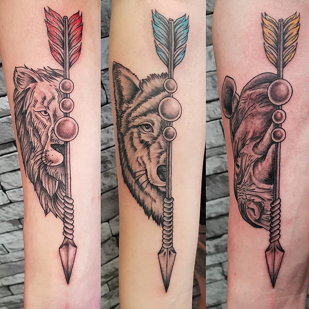 Matching tattoos featuring a lion, wolf, and rhinoceros with a vertical arrow, symbolizing strength, loyalty, and resilience